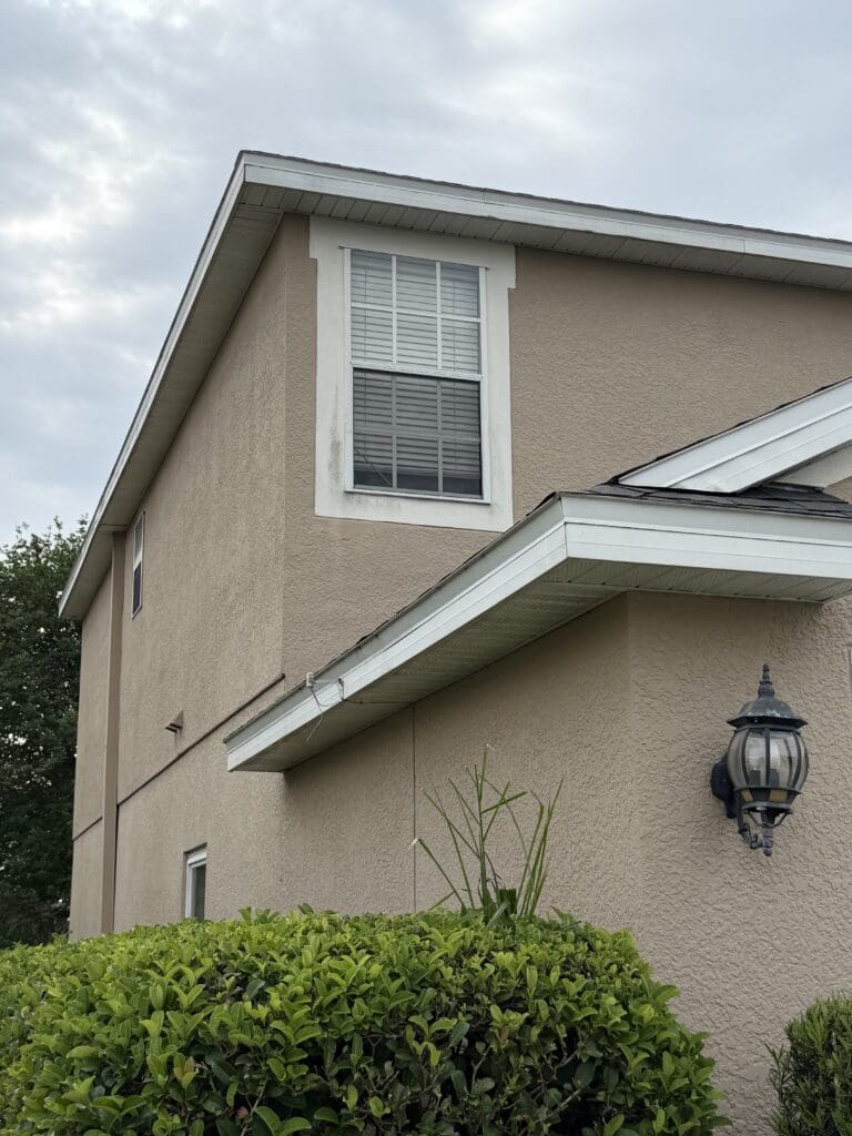 House exterior wall and gutters after soft washing in Orlando